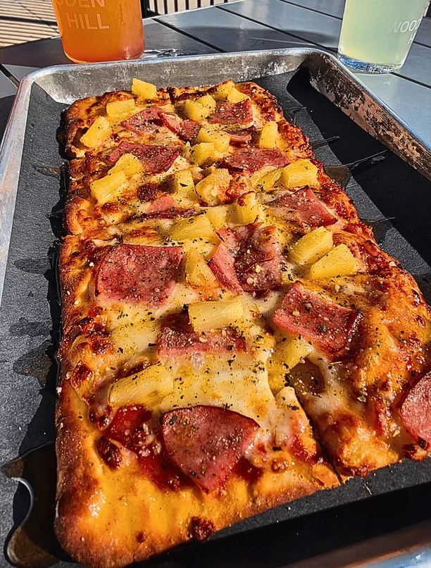 A Hawaiian flatbread on a metal tray.