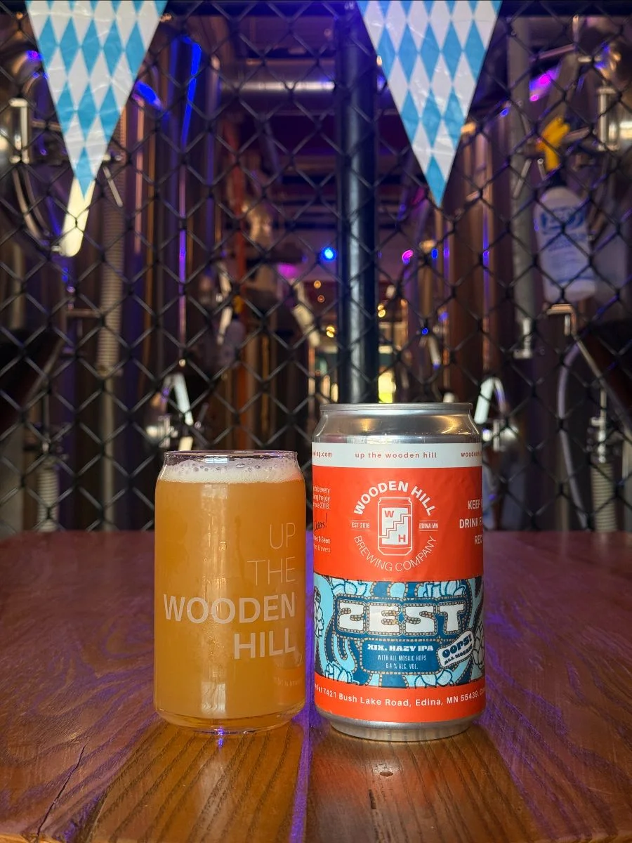 A glass of a hazy beer alongside a crowler can on Zest XIX