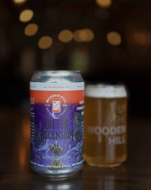 A Crowler can of Bitter Ascension with a glass of the beer behind
