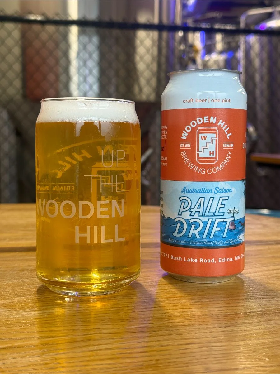 A glass of Pale Drift and a pint glass can with the logo