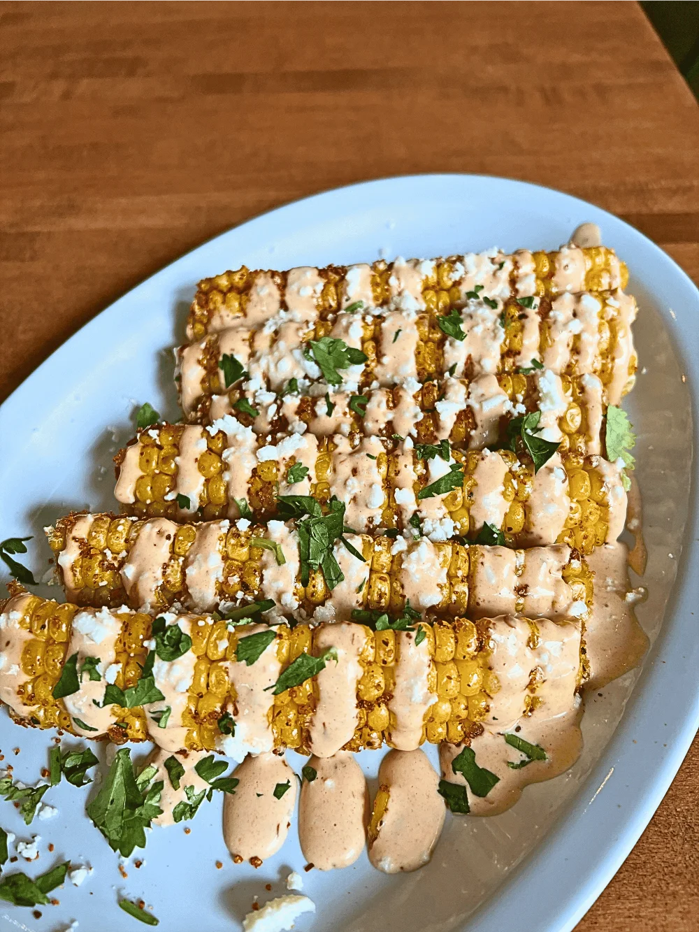 A plate of 6 corn ribs drizzled with toppings