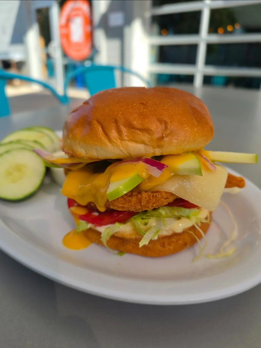 An apple honey mustard sandwich on a white plate with a side of veggies.