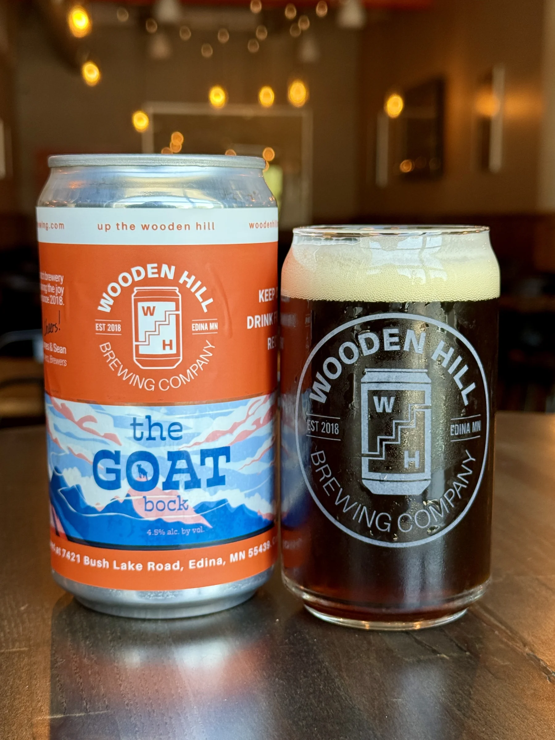A shot of a crowler can with the wooden hill logo and the goat label (left) a can-style glass of The Goat - a dark brown bock