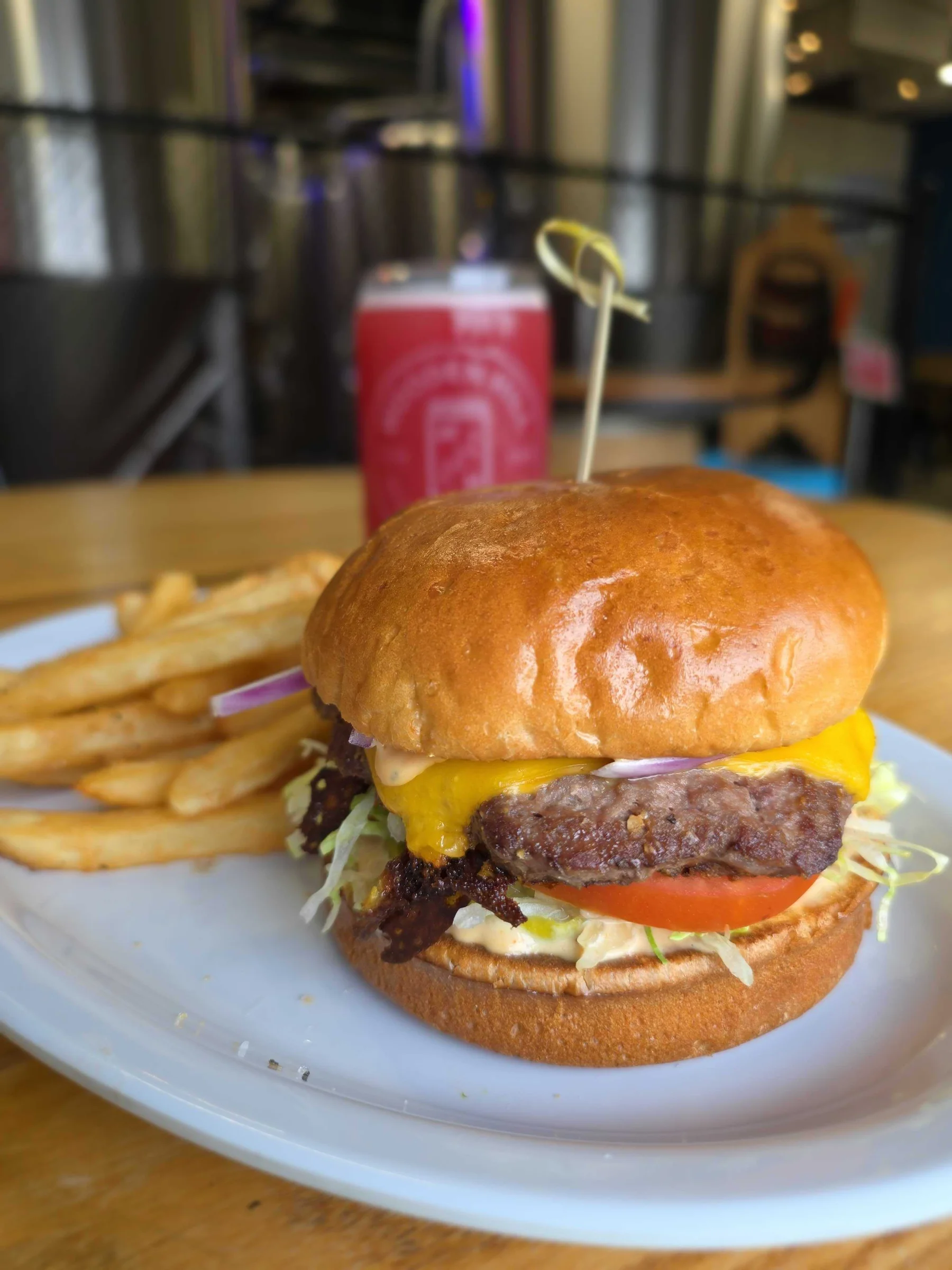 up and down burger on a plate with fries. Drink in the background.