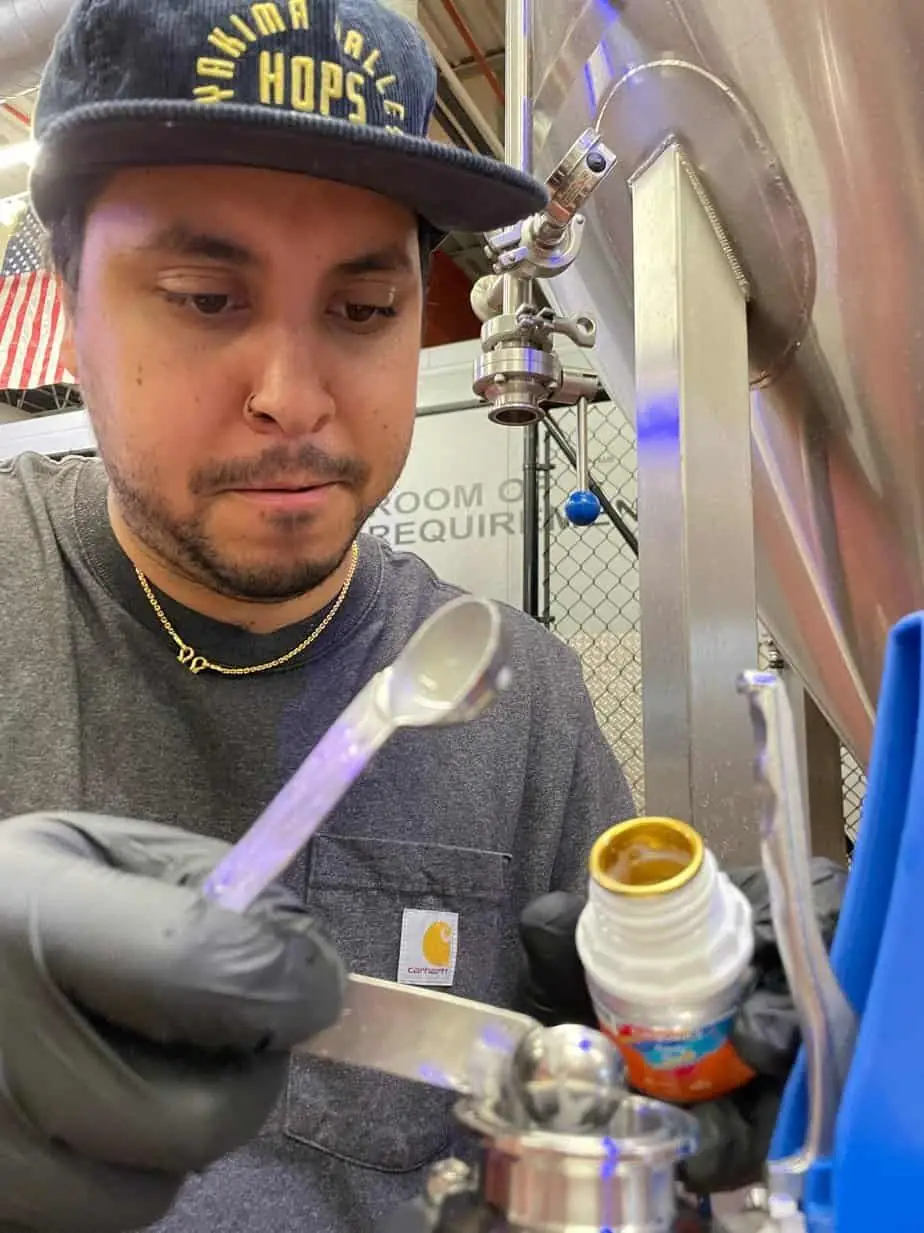 Photo of brewer pouring hop extract into a brewing vessel.