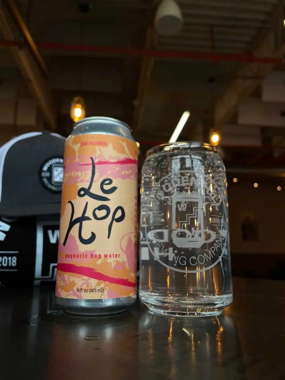 Can of Le Hop next to a glass of clear sparkling hop water