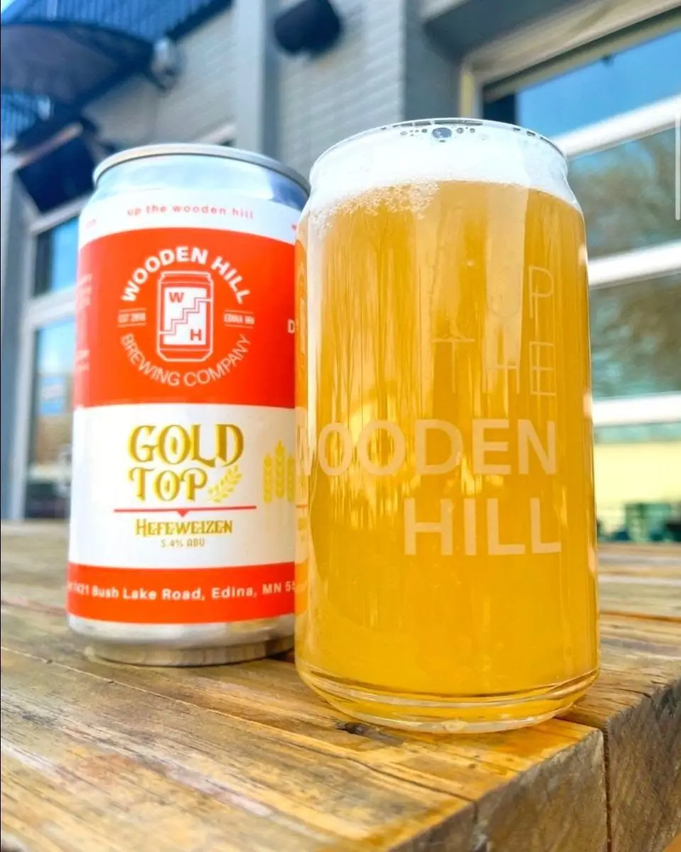 Picture of Gold Top (Hefeweizen) in a glass and the can of Gold Top in the background. Picture taken on front patio.