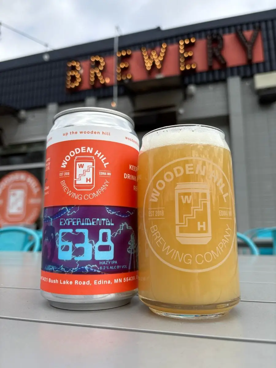 Picture of our new beer! - Experimental 638 with glass of beer next to it. Picture taken on the front patio with a "Brewery" sign in the back.