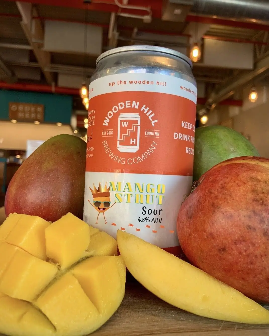 A picture of our Mango Strut beer can surrounded by real, fresh mangoes.