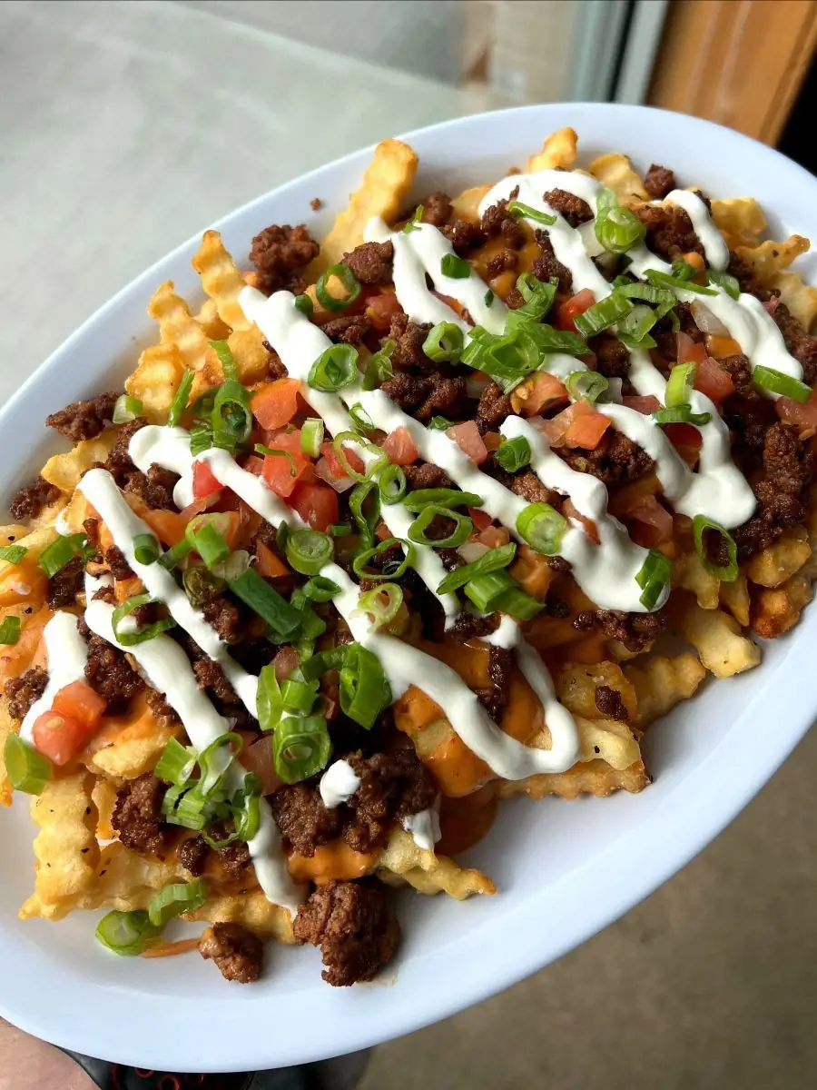 A picture of Nacho Fries loaded with toppings, a special menu item for Taco Wednesday