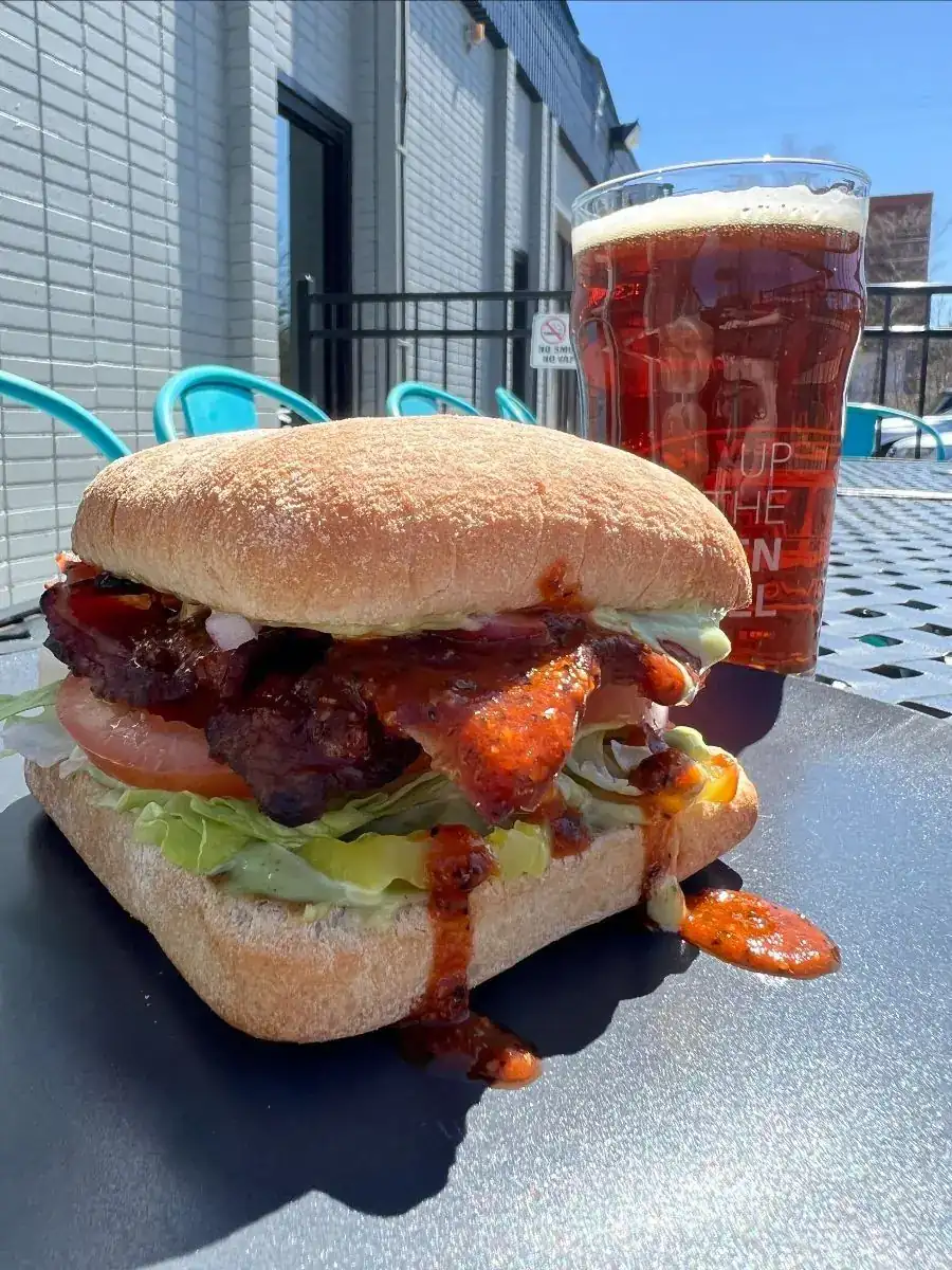 A picture of WH BLT sandwich with a glass of amber colored beer on the side. Picture taken on our front patio.