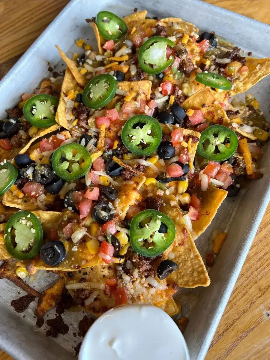 Picture of our Ballpark Nachos that are topped with cheese, ground beef, corn, black olives, tomato salsa, jalapenos and served with sour cream