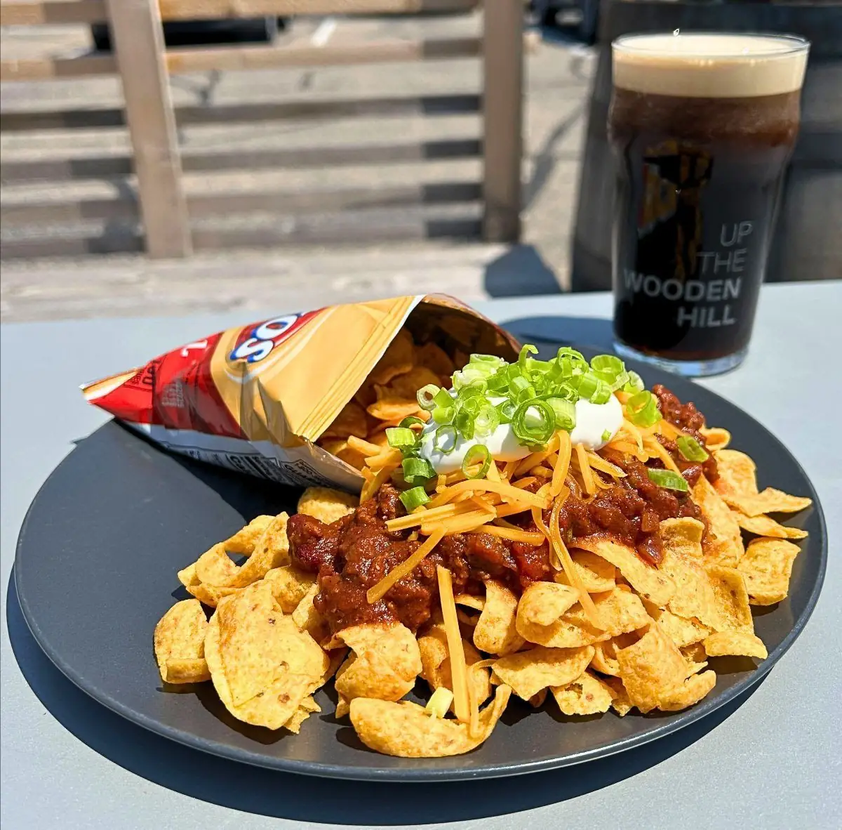 Picture of this week's taco special: Walking Chili Tacos! Picture shows the taco special on a black plate with a dark beer in the background.Picture was taken on our back patio.