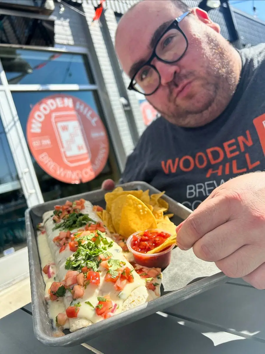 Image of a guy holding a tray scooping a chip into salsa with a smothered burrito also on the tray.