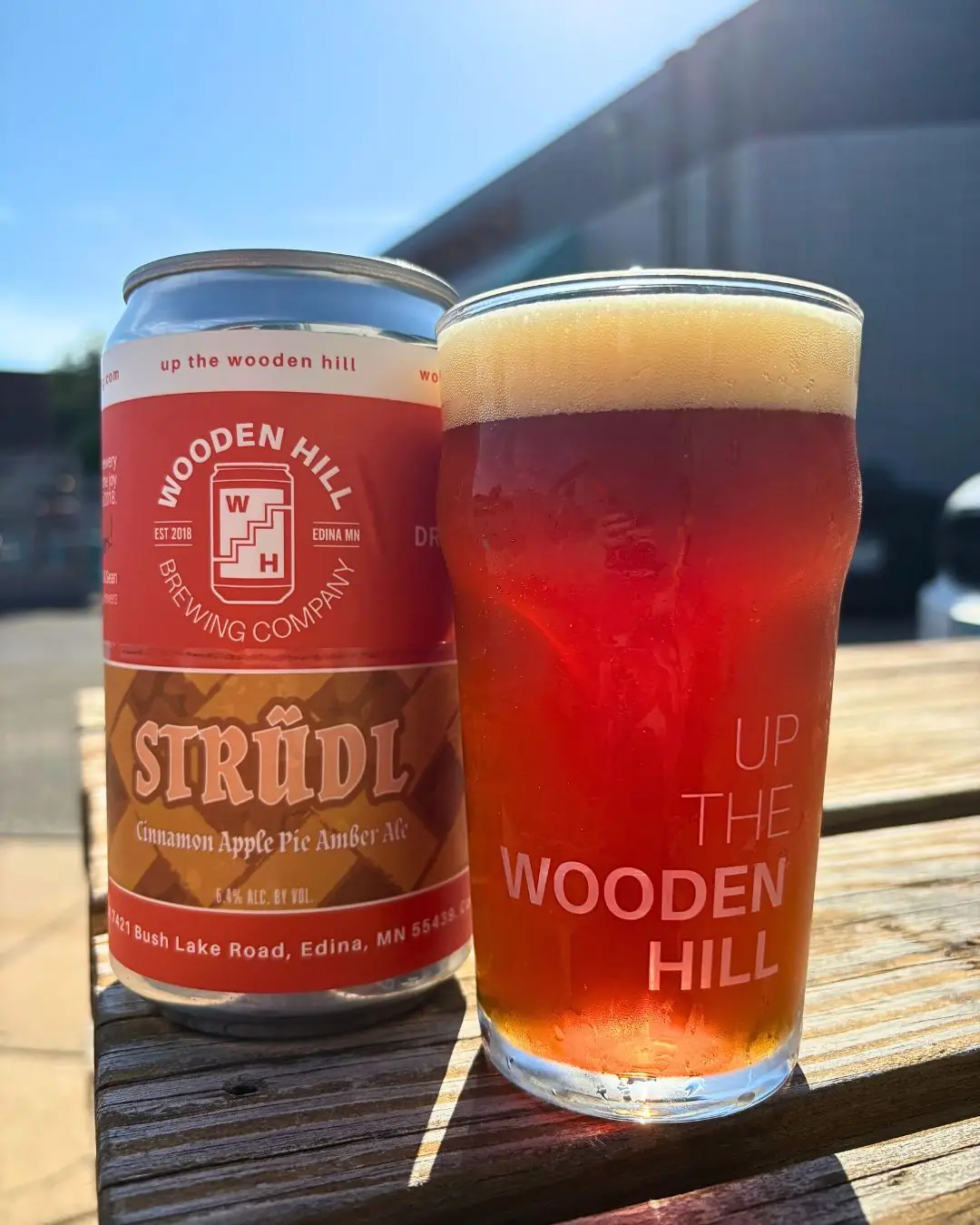 Image of Wooden Hill beer can of STRUDL which has an apple pie crust logo. On the right is a Wooden Hill glass with an orange colored beer in it.