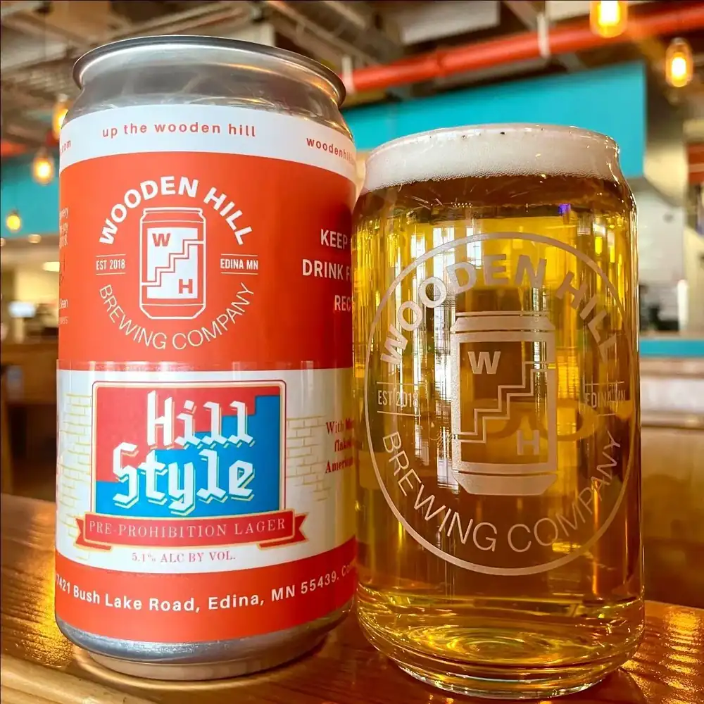 Picture of our Pre-Prohibition Lager, Hill Style! Picture shows both the can and a glass of the beer with the taproom in the backgroun.