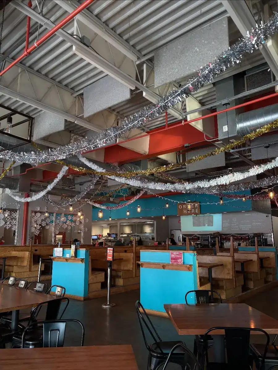Picture of our taproom decked out with holiday decorations such as tinsel hanging from the ceiling, string lights, and paper snowflakes on the windows.