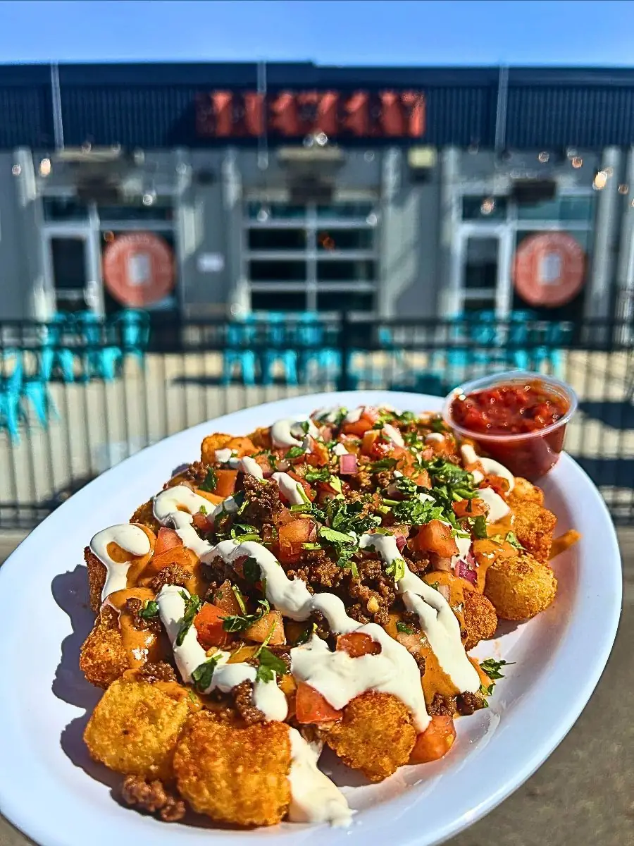 Plate fo totchos with Seasoned barrel tots House queso Taco seasoned ground beef House pico de gallo Chili lime crema Fresh cilantro