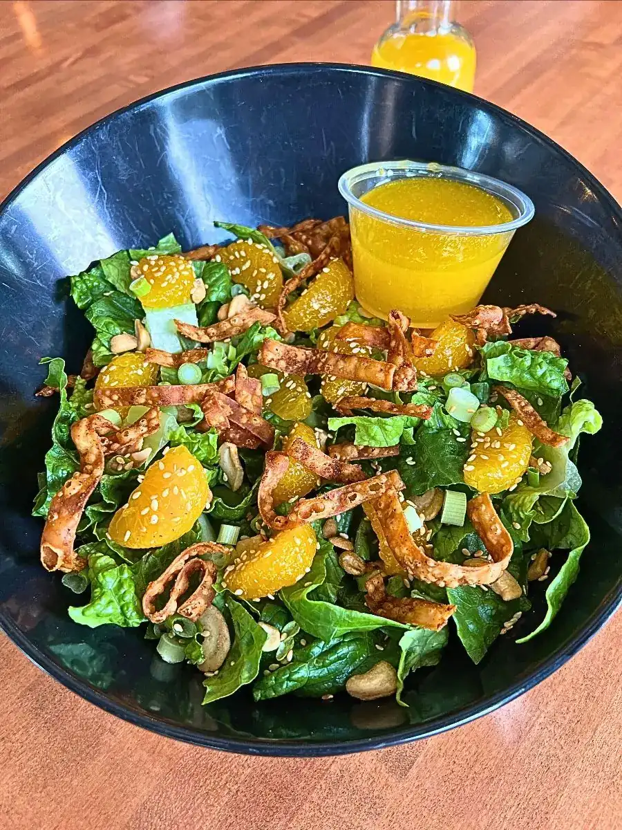 Mandarin Crunch Salad with Fresh lettuce Sweet mandarin orange Curry seasoned cashews Toasted sesame seeds Togarashi seasoned wonton strips Fresh cut green onion With a light and sweet mandarin lime vinaigrette