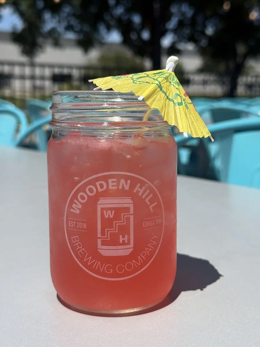 Picture of our newest seasonal cocktail - Patio Punch! The cocktail is in a mason jar with a mini yellow umbrella.