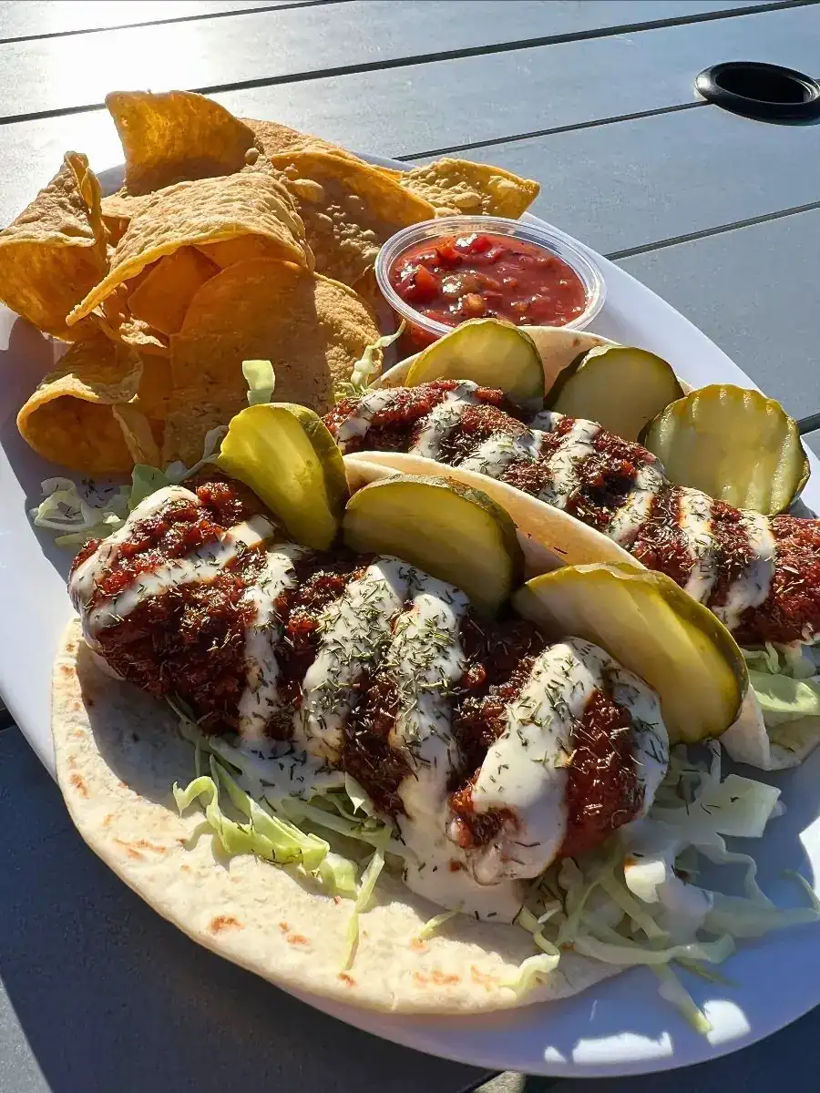 Image oftwo Nashville Chicken tacos on a plate with chips and salsa.