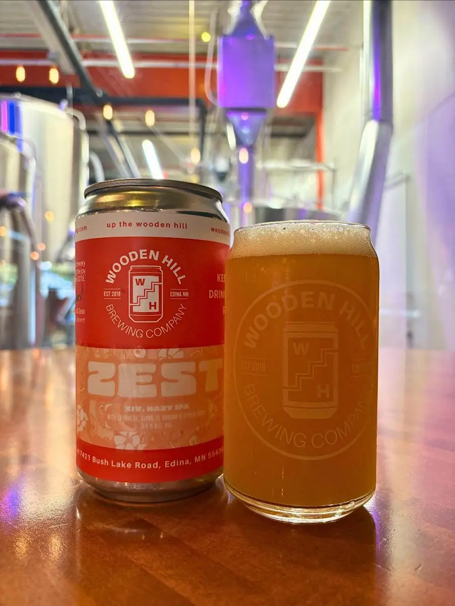 Can of Wooden Hill Zesxt XIV with peachy orange label. Wooden Hill branded glass of the Zest XIV beer on the right.