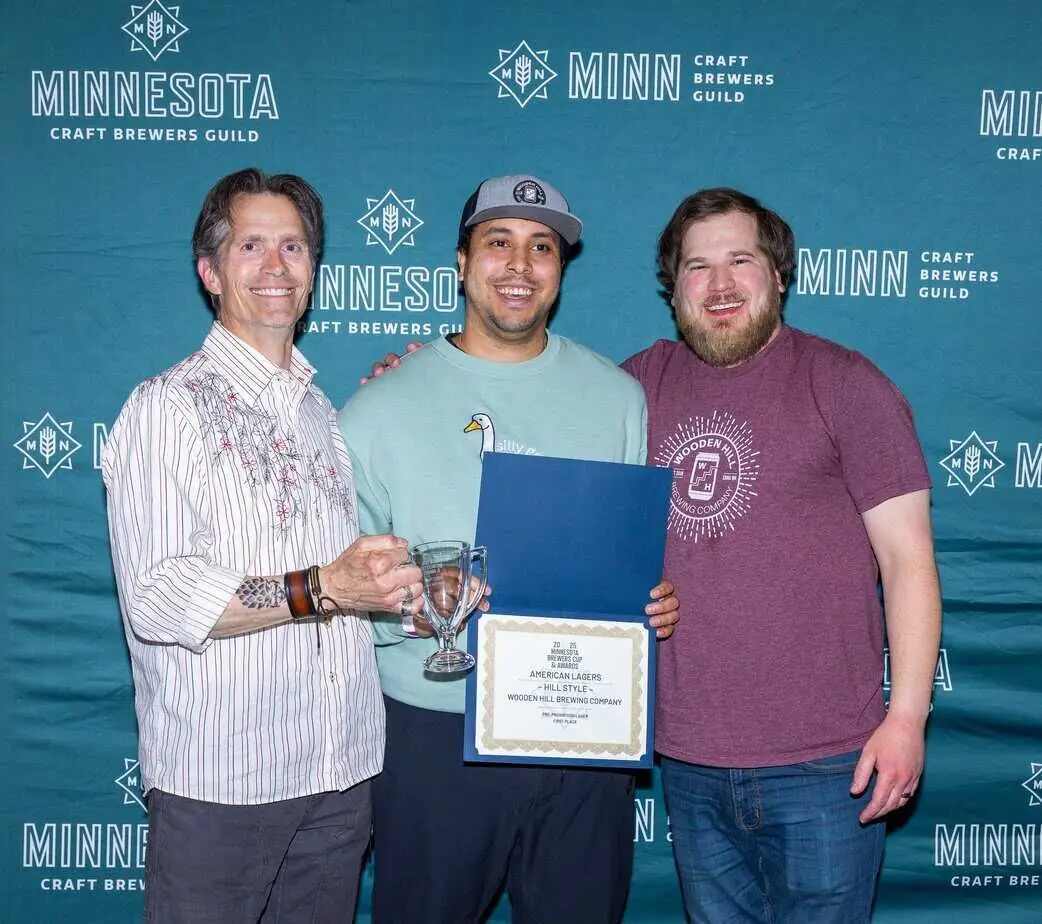 photograph of brewers Jeremy and Montana, with owner James Ewen with their award for best American Lager.