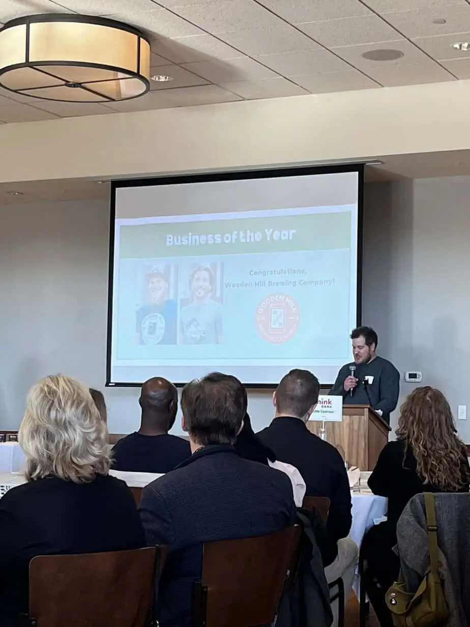 Photograph of Co-Founder James Ewen giving a speech in front of an audience, accepting the award for business of the year.